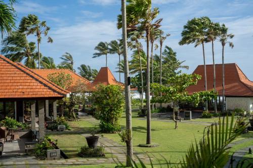 a row of houses with palm trees in a yard at Amarta Beach Retreat by Nakula in Tabanan