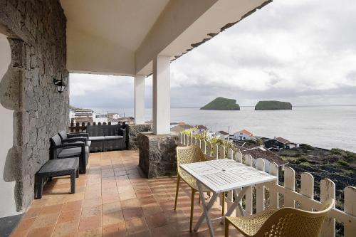 a patio with a table and chairs and the ocean at Breathe Nature - Beach House Azores in Feteira