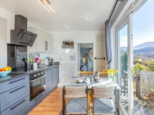 a kitchen with a table and chairs and a window at Hyfrydle Cottage in Talysarn