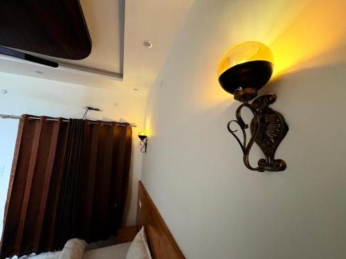 a light on the wall of a room with a bed at GJ Wellness And Stay in Rishīkesh