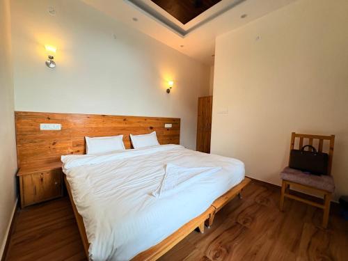 a bedroom with a large white bed and a chair at GJ Wellness And Stay in Rishīkesh