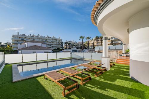 an outdoor patio with a swimming pool and benches at Villa Thetis by Atlantic Places in Albufeira