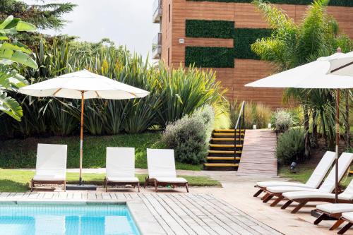 a group of chairs and umbrellas next to a pool at Oceana Suites Mansa Inn in Punta del Este