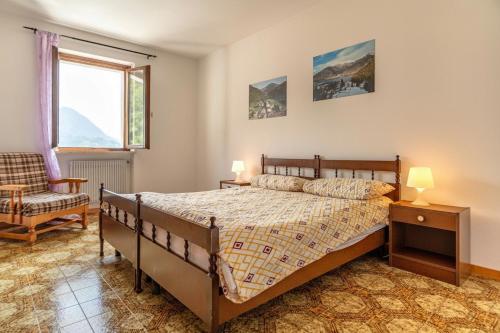 a bedroom with a bed and a chair and a window at Casa Maria in Mezzolago