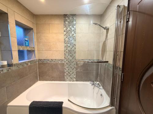 a bathroom with a bath tub and a sink at 4-Bed Barnwell Retreat- Sleeps10 Garden & Parking in Stevenage