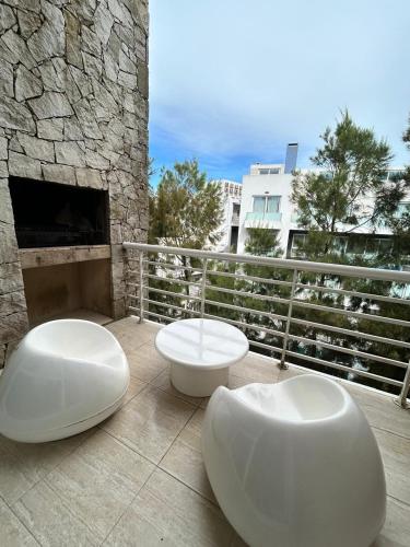 two white chairs sitting on a patio with a fireplace at Sea Point By D&G in Carilo