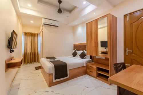 a bedroom with a bed and a desk and a television at Grace Apart Hotel @Kochi in Cochin