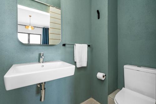 a bathroom with a sink and a mirror and a toilet at Cape on Popham 21B in Bloubergstrand