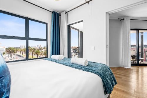 a bedroom with a large bed and large windows at Cape on Popham 21B in Bloubergstrand
