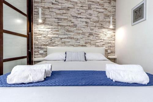 a bedroom with a white bed with a brick wall at NURAS - Joia city center in Alghero