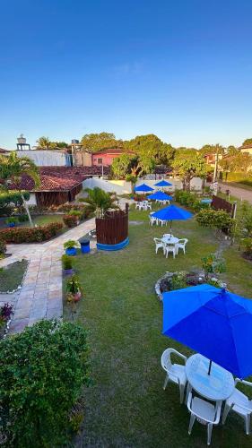 a group of tables and blue umbrellas on a lawn at Pousada Meu Sossego in Barra Grande