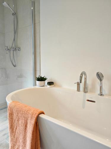 a bath tub with a shower and a towel at Au Bon Cap in Hervelinghen