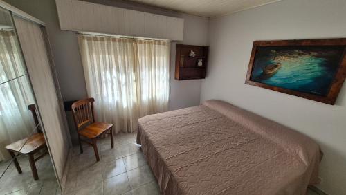 a bedroom with a bed and a chair and a painting at Betania in Carhué