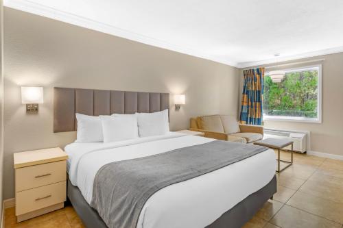 a bedroom with a large white bed and a chair at Orlando International Drive North Hotel in Orlando