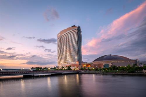 a tall building next to a river with a bridge at Hilton Fukuoka Sea Hawk in Fukuoka