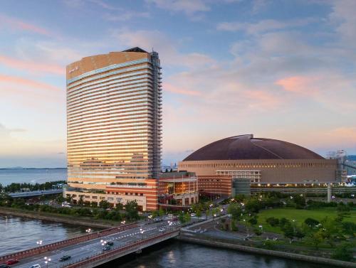 a tall building next to a river with a bridge at Hilton Fukuoka Sea Hawk in Fukuoka