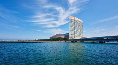 a tall building next to the water with a bridge at Hilton Fukuoka Sea Hawk in Fukuoka