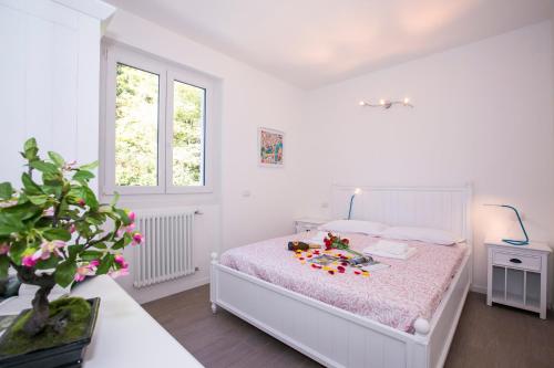 メナッジョにあるCasa Laura Apt. 6の白いベッドルーム(花の飾られたベッド付)