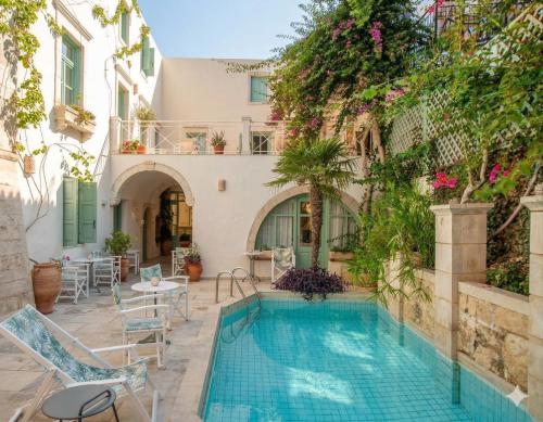 a pool in the courtyard of a building with a house at Mythos Suites Boutique Hotel in Rethymno