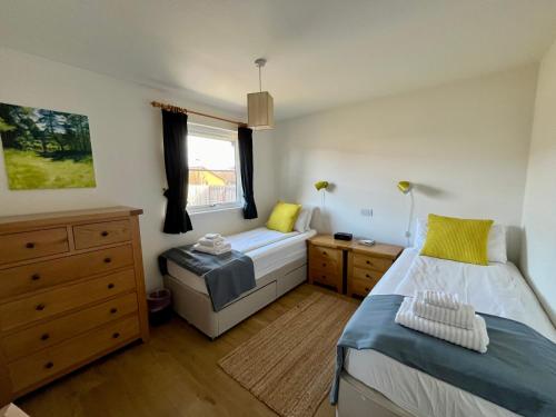 a bedroom with two beds and a window at Blaeberry Cottage in Aviemore