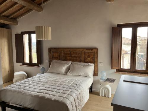 a bedroom with a bed and a table and two windows at La casina del borgo - Monolocale Nettuno in Perugia