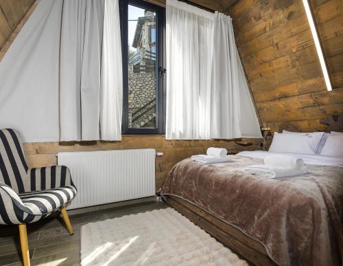 a bedroom with a bed and a chair and a window at LF Parnassos Chalet in Eptalofos