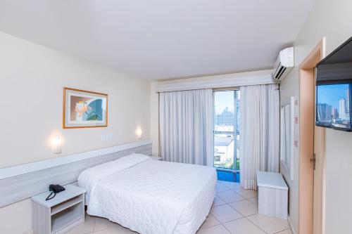 a hotel room with a bed and a television at Hotel Suárez Executive Novo Hamburgo in Novo Hamburgo