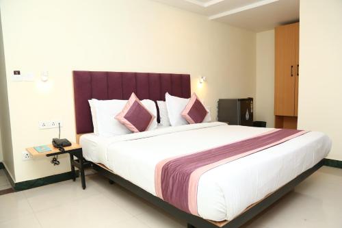 a bedroom with a large bed with pink pillows at SoonStay Konark Inn in Indore