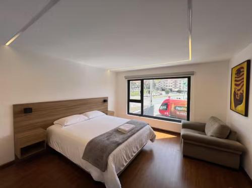 a bedroom with a bed and a couch and a window at Cuenca Hotel Apartment in Cuenca