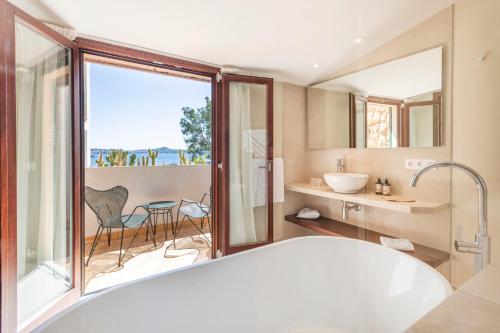 a bathroom with a tub and a view of the ocean at Hotel Cala Fornells in Paguera