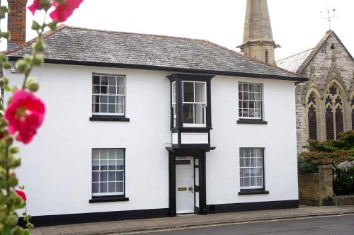 a white house with black windows and a church at Landguard - Yarmouth in Yarmouth