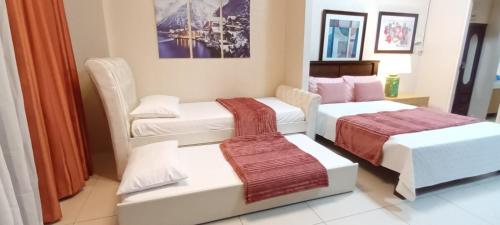 a hotel room with two beds and a couch at Shirley Pico de Loro 1BR in Nasugbu