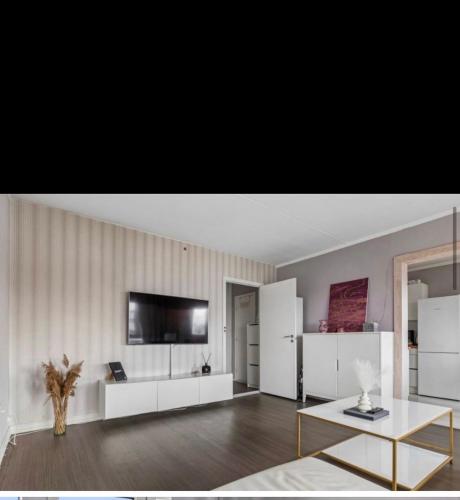 a living room with a table and a tv on a wall at Cozy spot, Free Netflix and Prime in Vallensbæk