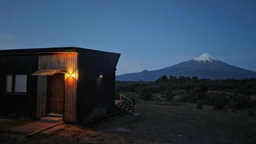 a small building with a mountain in the background at Casa Vulkaan in Puerto Varas