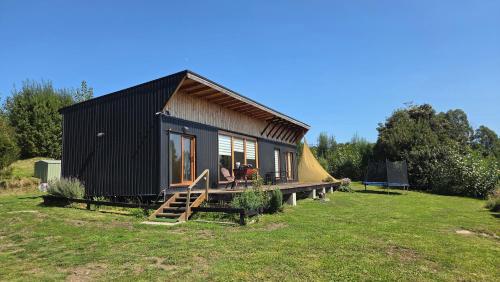 a black tiny house with a tent in a field at Casa Vulkaan in Puerto Varas