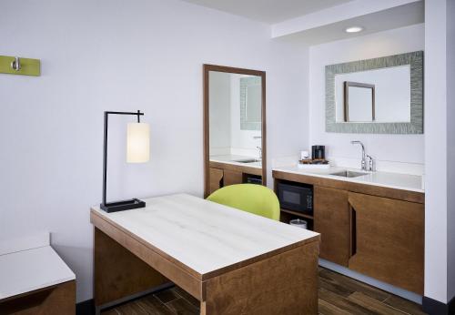 a bathroom with a sink and a desk with a mirror at Hampton Inn & Suites by Hilton Windsor in Windsor