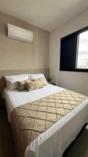 a bedroom with a large bed with a window at Studio moderno, rooftop com piscina, próx UFU in Uberlândia