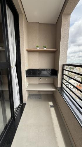 a room with a balcony with two plants on shelves at Studio moderno, rooftop com piscina, próx UFU in Uberlândia