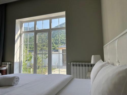 a bedroom with a white bed and a large window at Qafqaz Hills Villa in Gabala