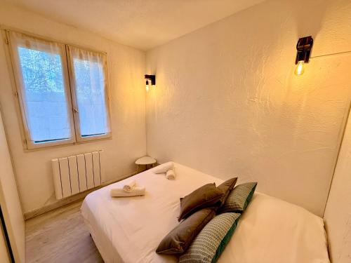a bedroom with a bed with pillows and a window at Le Cosy du Lagon bleu in Fréjus
