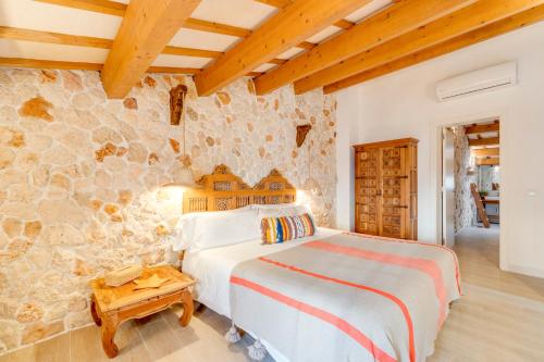 a bedroom with a bed and a stone wall at Calma Hotel in Ciutadella