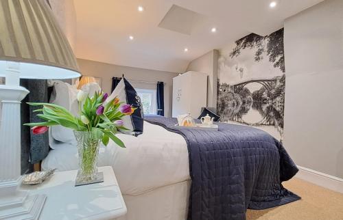a bedroom with a bed with a vase of flowers on a table at Ironbridge View Townhouse - WINNER 2026 UK MOST PICTURESQUE SELF-CATERING HOLIDAY HOME & 2026 SELF-CATERING ACCOMMODATION OF THE YEAR in Ironbridge