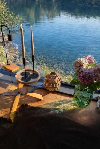 a table with two candles and flowers next to a lake at Paul Lake Escape Residence in Novosëlki