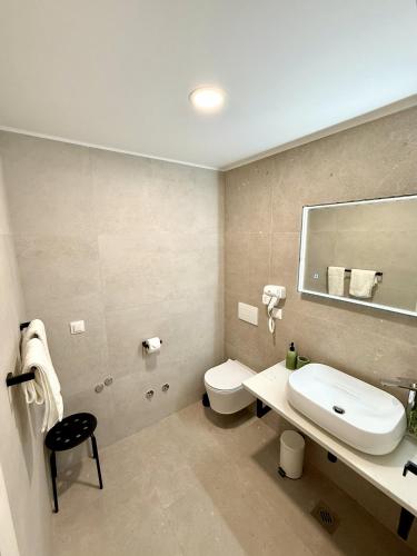 a bathroom with a sink and a toilet and a mirror at Cloud9 Airport Suites in Močići
