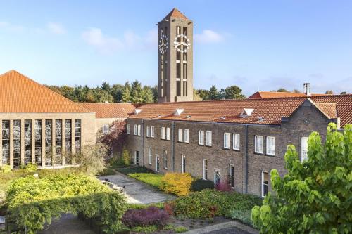 a large brick building with a clock tower in the background at NH Eindhoven Conference Centre Koningshof in Veldhoven