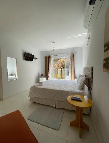 a bedroom with a bed and a table and a window at Rosa Spa e Pousada in Aparecida de Goiânia