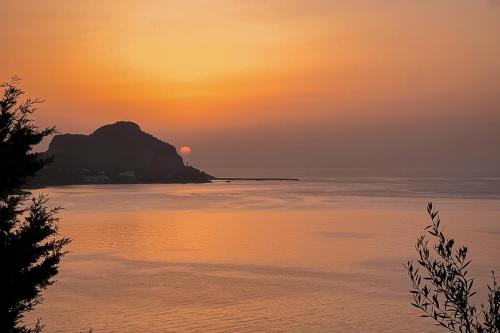 a sunset over a body of water with a rock formation at Villa Magliolo Panoramic Luxury Retreat in Cefalù