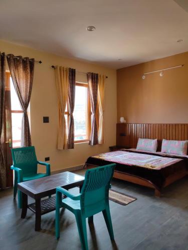 a bedroom with a bed and two chairs and a table at Hill Side Heaven Homestay in Nainital