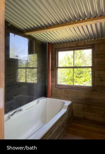 a white bath tub in a room with two windows at The Quarry Caravan in Falmouth