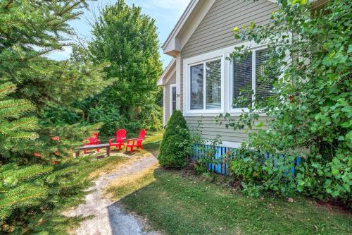 a house with two red chairs in the yard at The Bluebird - 34 Meadow View in Cherry Valley